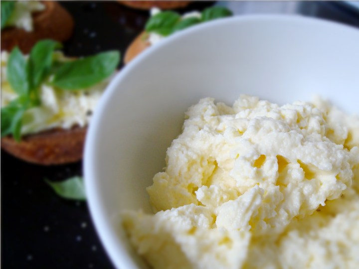 Ricotta in a bowl with basil on toast